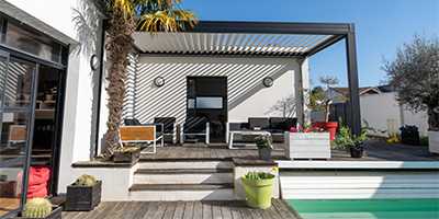 pergola bioclimatique adossée en aluminium près d'une piscine