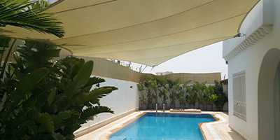 voile beige polygonale installée près d'une piscine